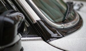 Gloss black vinyl wrap applied to white car window trim during a chrome delete