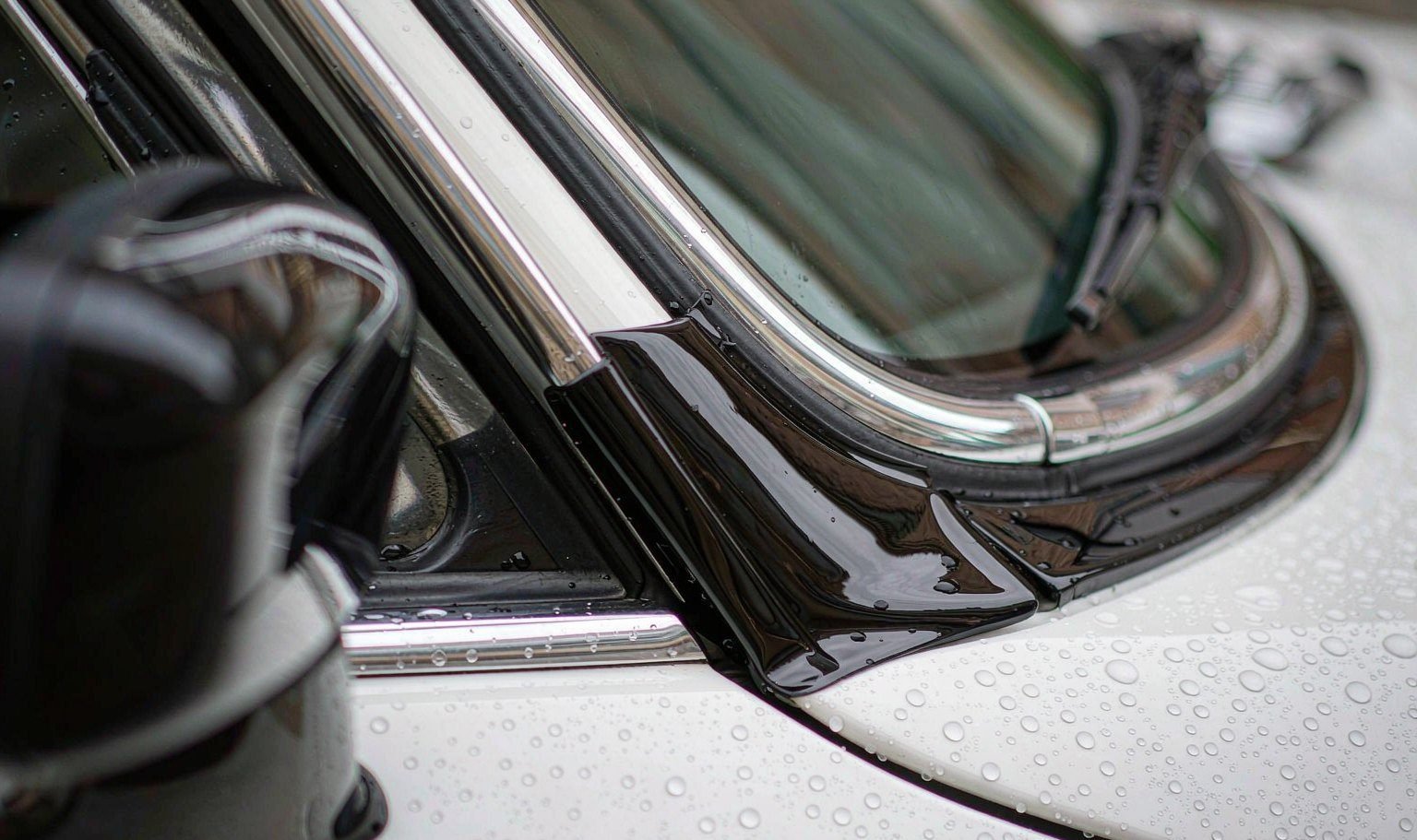 Gloss black vinyl wrap applied to white car window trim during a chrome delete