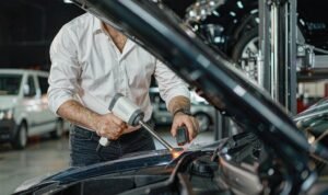 Installer post-heating a Clear TPU PPF edge on a car hood with an IR thermometer in a clean workshop
